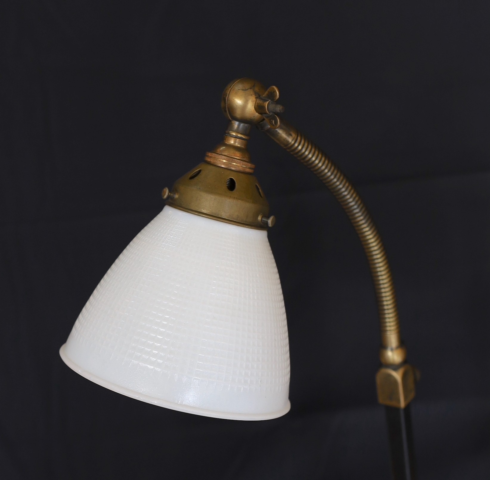 A 1930s English brass wrought iron and cast iron adjustable desk lamp with moulded opaque glass shade, height 66cm